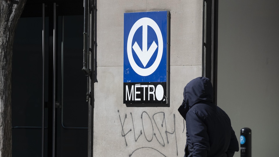 Une personne s'approche de l'entrée d'une station du métro de Montréal.