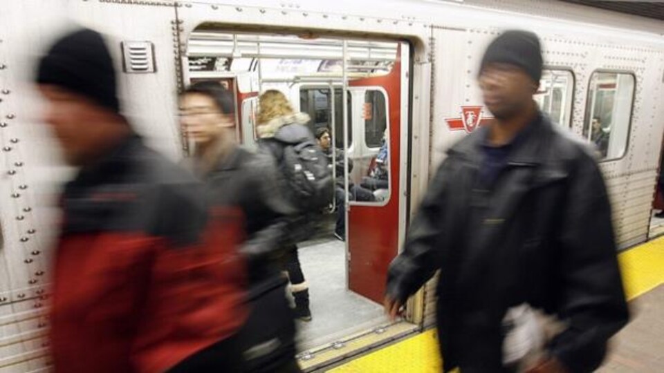 Des passagers du métro se déplacent sur le quai près d'une rame.
