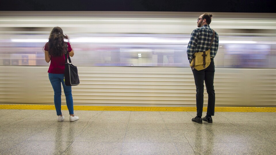 Un jeune homme et une jeune femme attendent le métro sur une plateforme à Toronto.