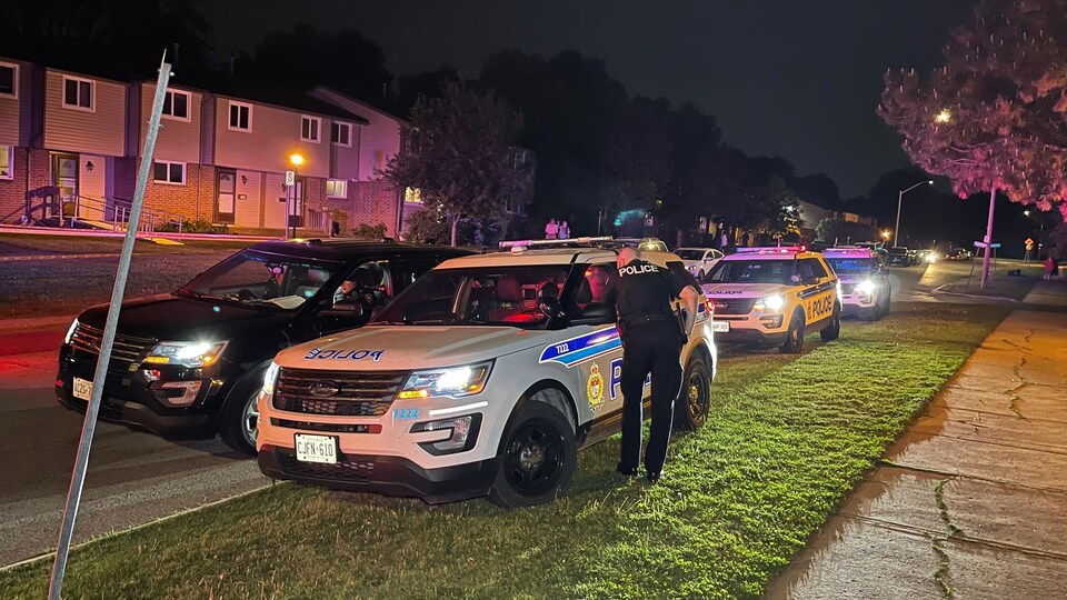 Une demi-douzaine de voiture de police dans un quartier résidentiel la nuit.