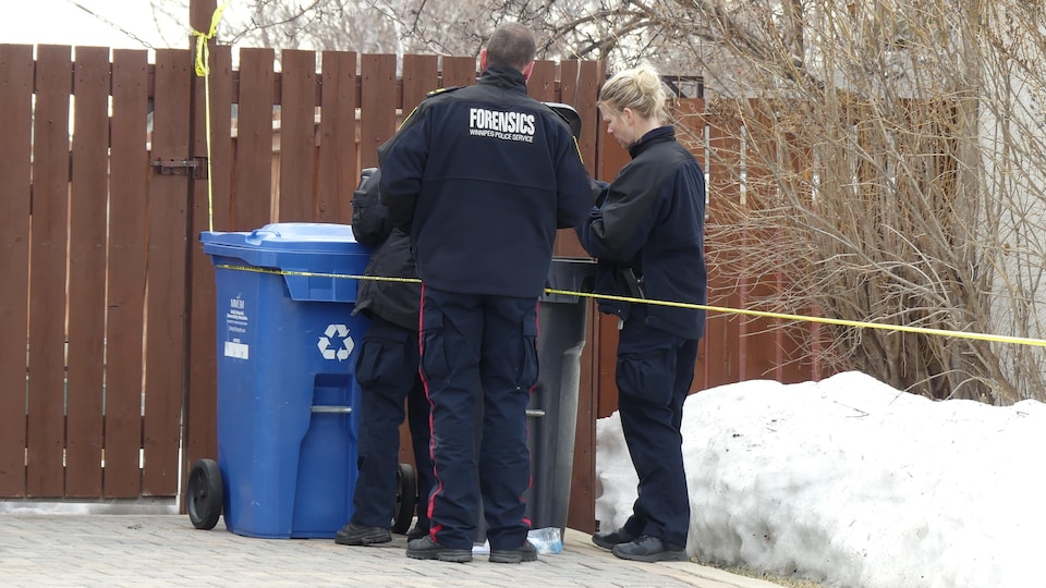 Des policiers fouillent une poubelle.