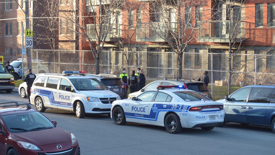 Deux voitures de police sont stationnées devant l'immeuble.