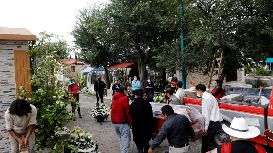 Des travailleurs de pompes funèbres transportent un cercueil d'une victime de la pandémie, à Mexico, la capitale du Mexique.