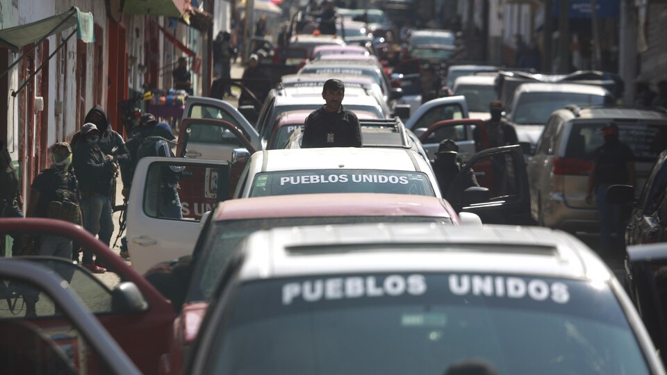 Une file d'automobiles avec les mots «Pueblos Unidos» écrits sur chaque pare-brise.