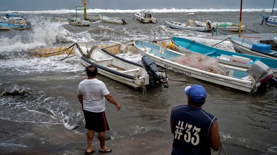Des pêcheurs se préparent à retirer des bateaux du quai à l’approche d’un ouragan.