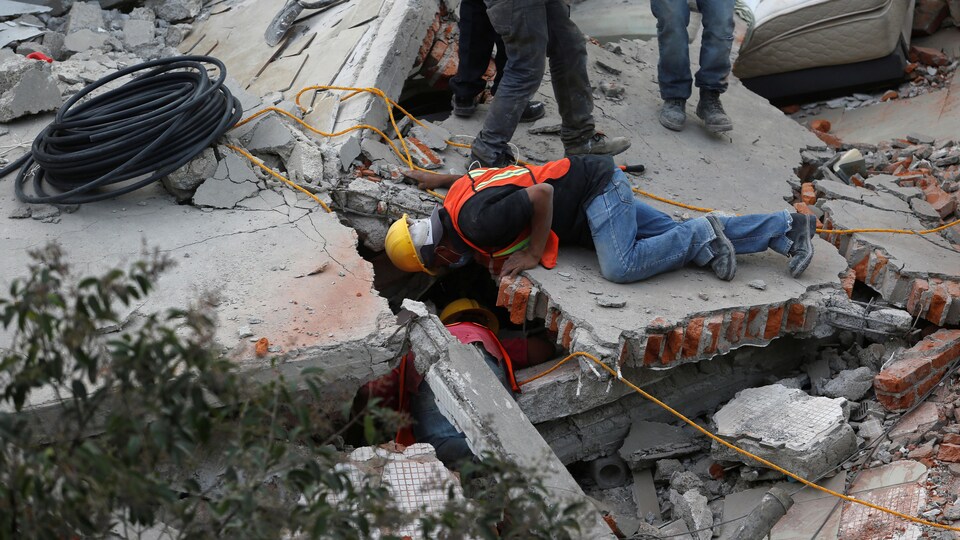 Des secouristes tentent de retrouver des victimes coincées sous les décombres d'un immeuble, à Mexico.