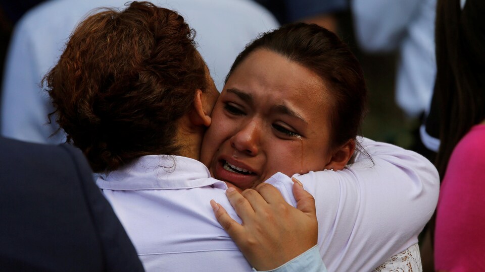 Une femme en larmes en serre une autre dans ses bras.