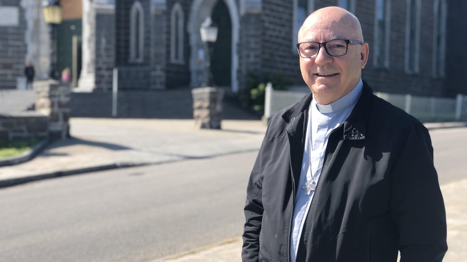 Mgr René Guay devant une église.