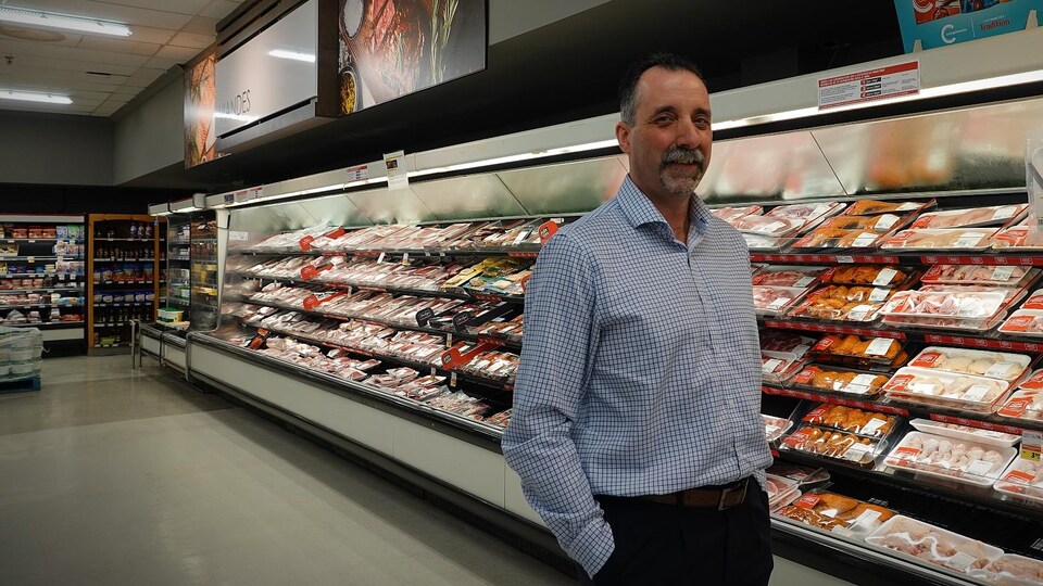 Jacques Chiasson, directeur de la Coopérative de Lamèque, debout devant un rayon de viandes à l'épicerie.