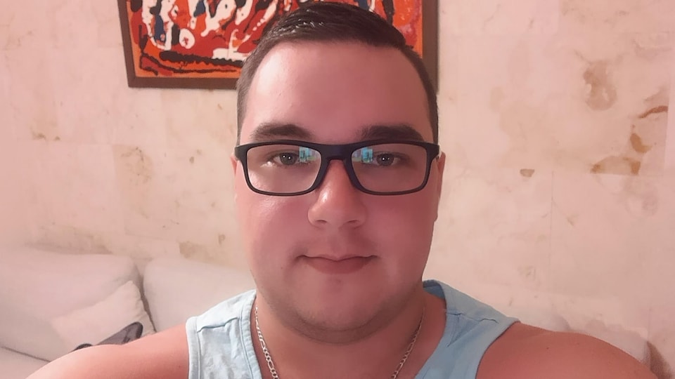 Photo de l'accusé portant des lunettes noirs et une camisole bleue.