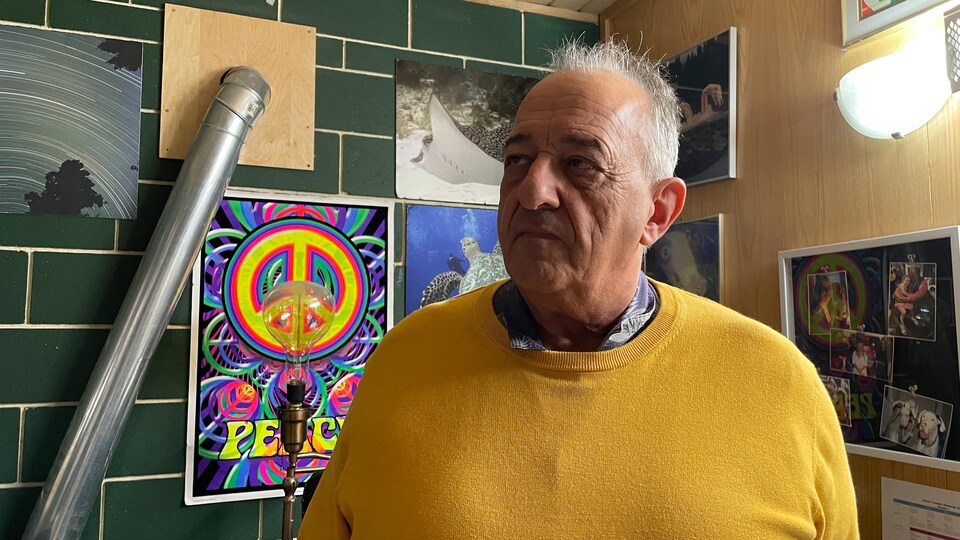 Michael Guzzi debout dans son bureau, devant un mur rempli d'oeuvres d'art.