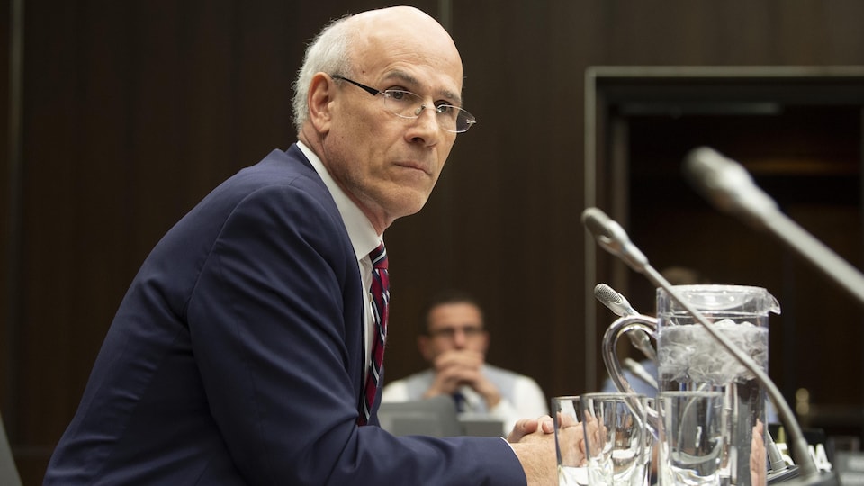 Michael Wernick, assis à une table, devant un micro.