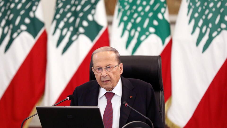 Le président Aoun prononçant un discours devant plusieurs drapeaux libanais.