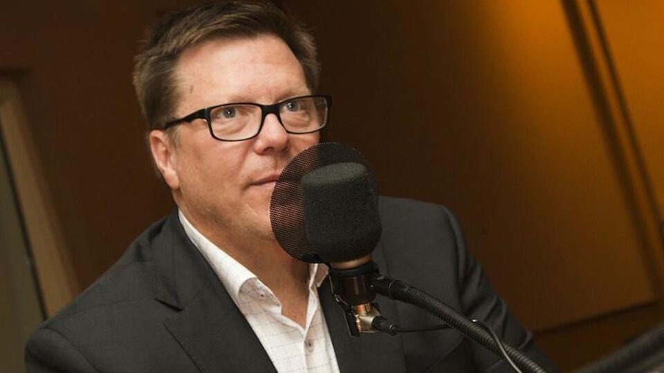 Michel Juneau-Katsuya devant un micro, dans un studio.