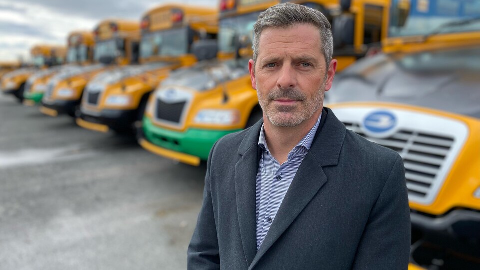 Mr. Labrie poses in front of a line of buses.