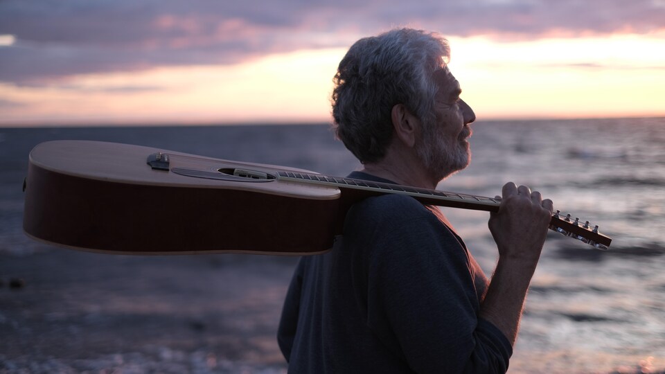 Michel Lalonde, sa guitare reposant sur son épaule.