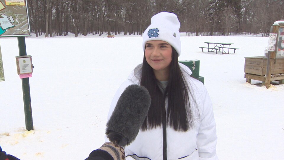 Mishel Staropinets vêtue d'un manteau blanc et d'une tuque blanche donne une entrevue à Radio-Canada à l'extérieur dans un parc.