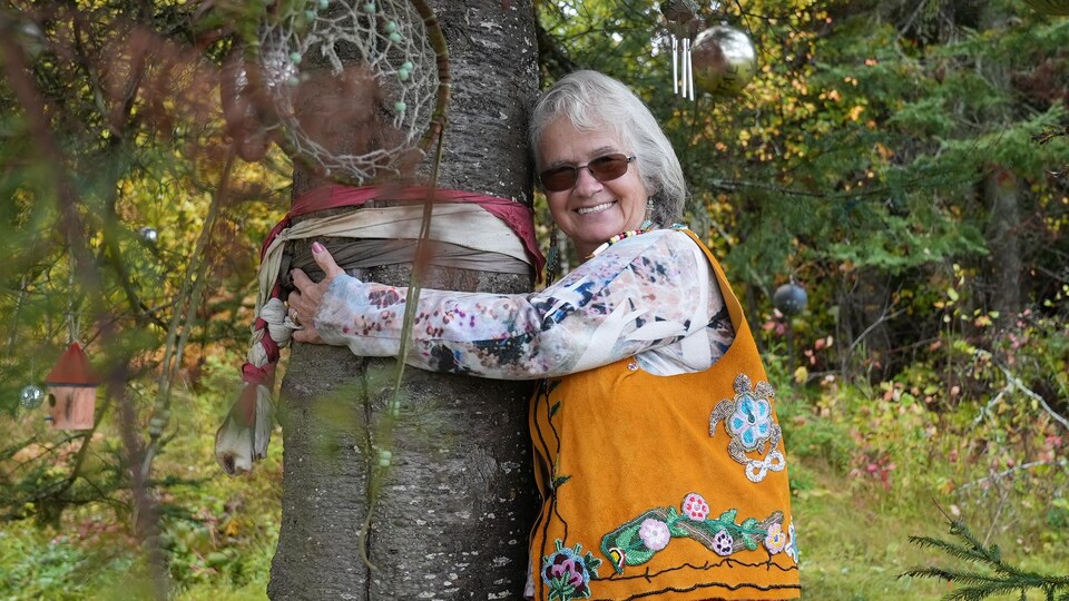 Une femme donne un câlin à un arbre.
