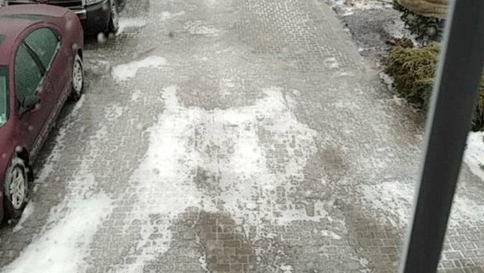 Une entrée de maison et les véhicules qui y sont garés sont recouverts de glace.