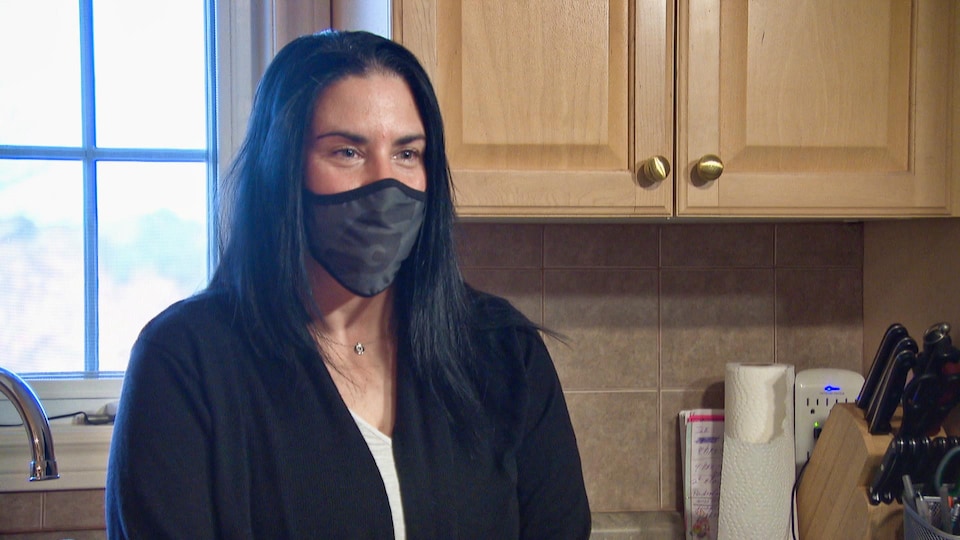 Une femme avec un masque à l'intérieur d'une maison. 