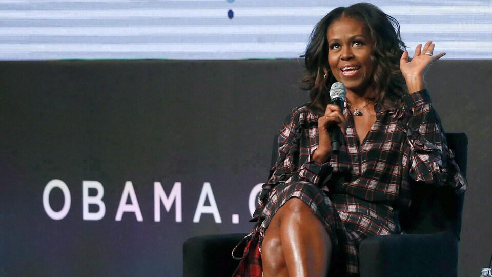 Assise, Michelle Obama fait un signe de la main. 