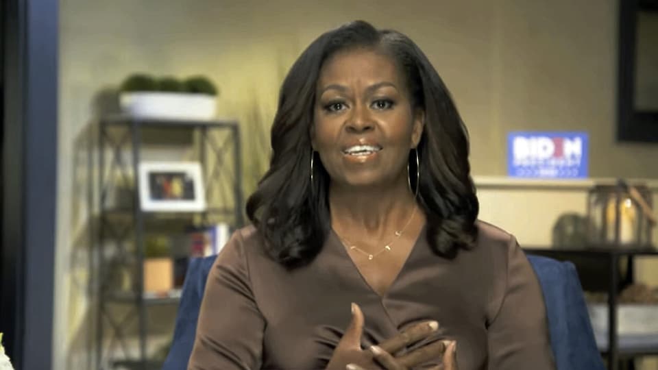 Michelle Obama assise les mains sur le cœur.