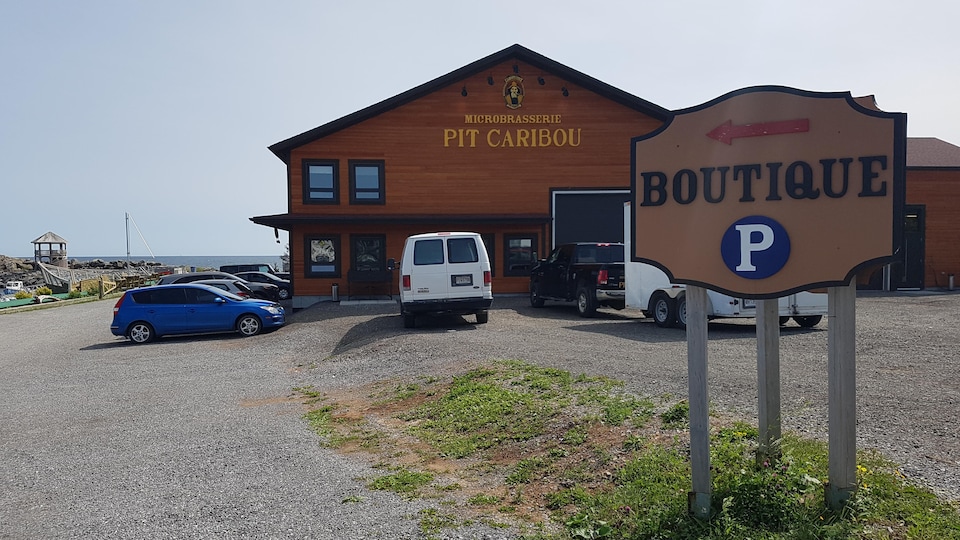 Bâtiment de bois situé au bord de l'eau. À l'avant-plan, une affiche sur laquelle on peut lire «Boutique».
