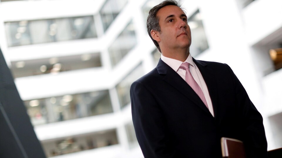 Michael Cohen, debout, avec un dossier en main.
