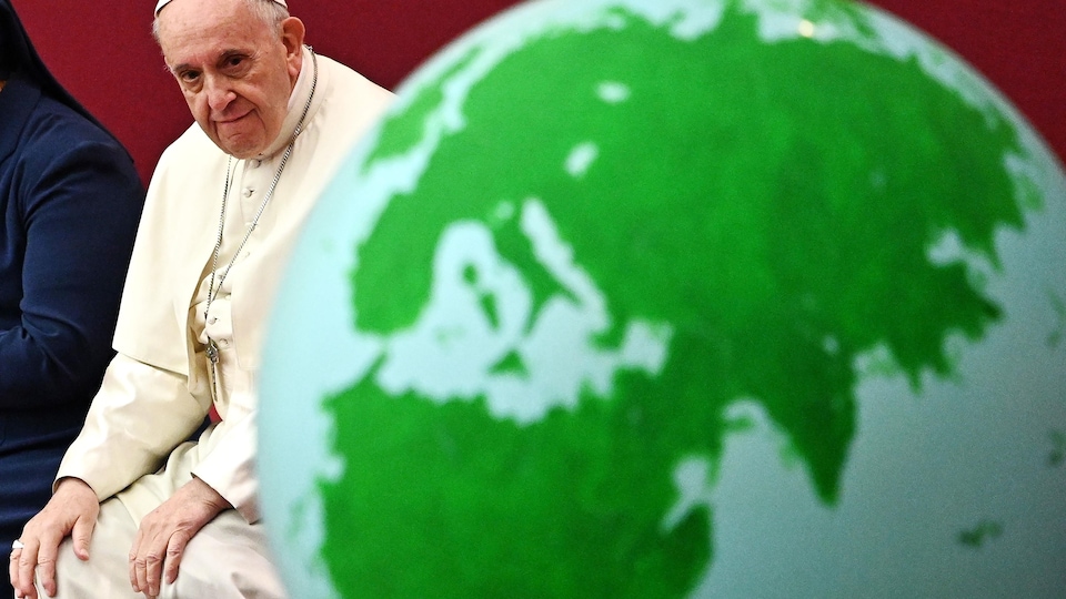 Le pape François regarde un globe terrestre.