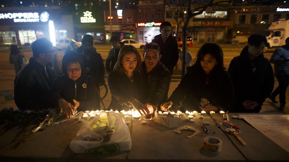Des Torontois déposent des chandelles sur un palissade commémorative rendant hommage aux victimes de l'attaque au camion-bélier.