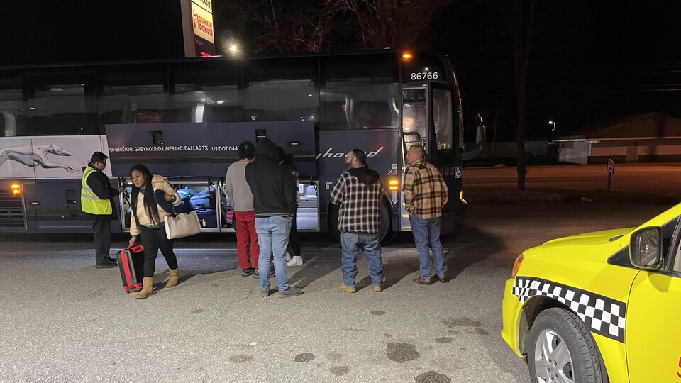 Une migrante sort ses bagages d'un autobus.