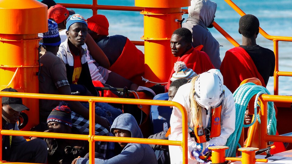 Des migrants africains sont assis sur le pont du bateau.