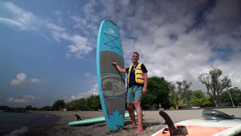 Mike Shoreman se situe sur la plage avec une planche à pagaie.