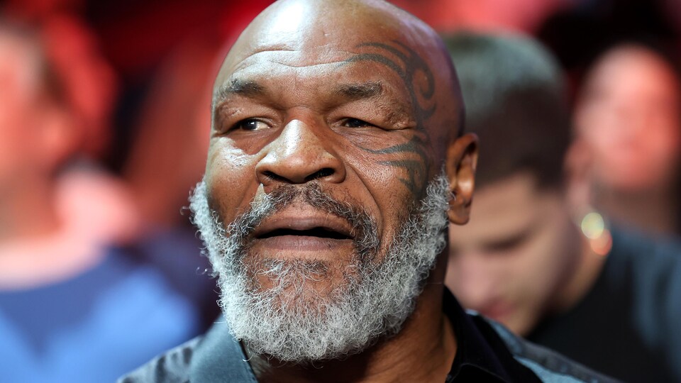 Portant une barbe blanche, Mike Tyson se trouve dans une foule.