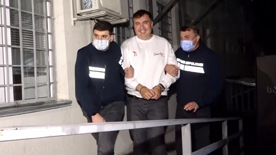 Mikheïl Saakachvili est menotté et escorté par deux policiers dans une prison géorgienne.