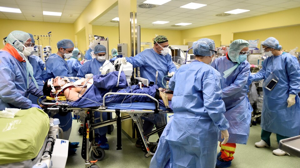 Des travailleurs de la santé s'occupent d'un patient atteint de la COVID-19 dans une unité de soins intensifs de l'hôpital San Raffaele à Milan, en Italie, le 27 mars 2020.