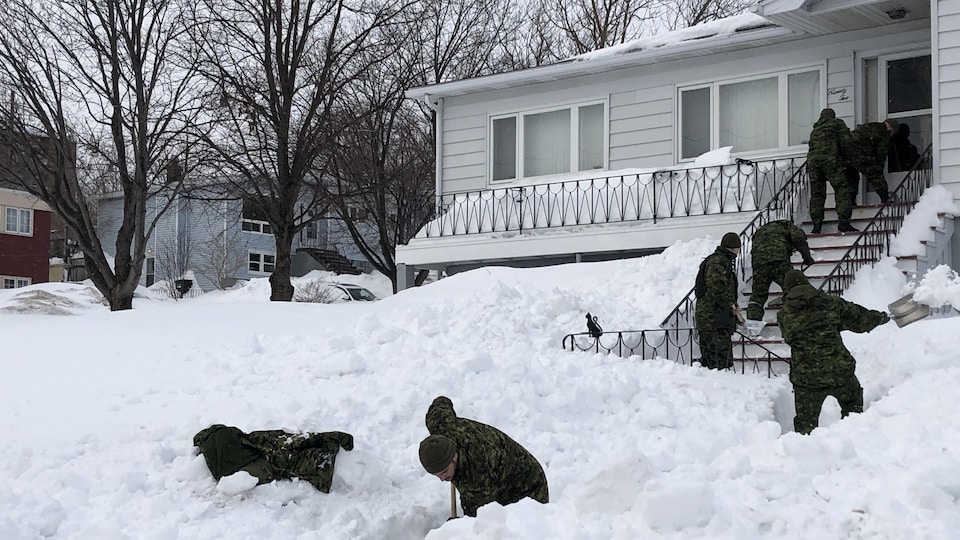 Des militaires déblaient l'entrée d'une résidence à Terre-Neuve.