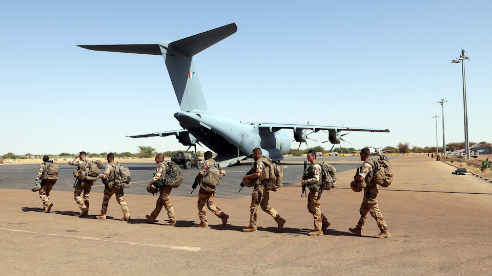 Des soldats s’apprêtent à monter à bord d’un avion.