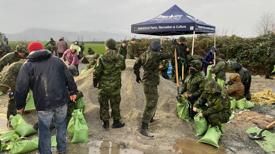 Des militaires aident des habitants d'Abbotsford à remplir des sacs de sable.