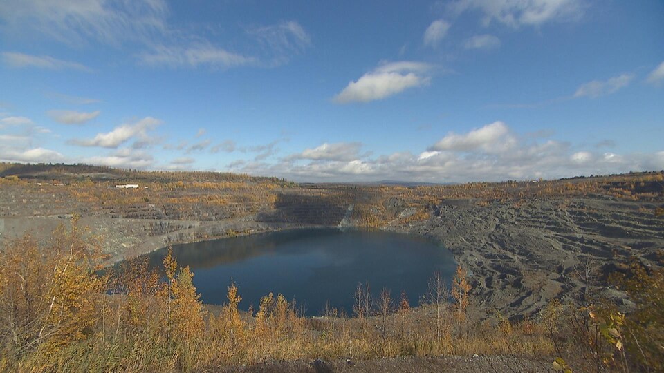 Le fond du gros trou de la mine est rempli d'eau foncée.