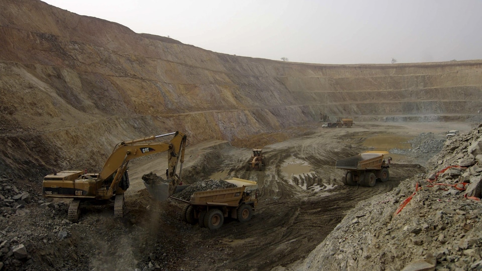 Une grue dispose du minerai dans d'immenses camions de chargement.