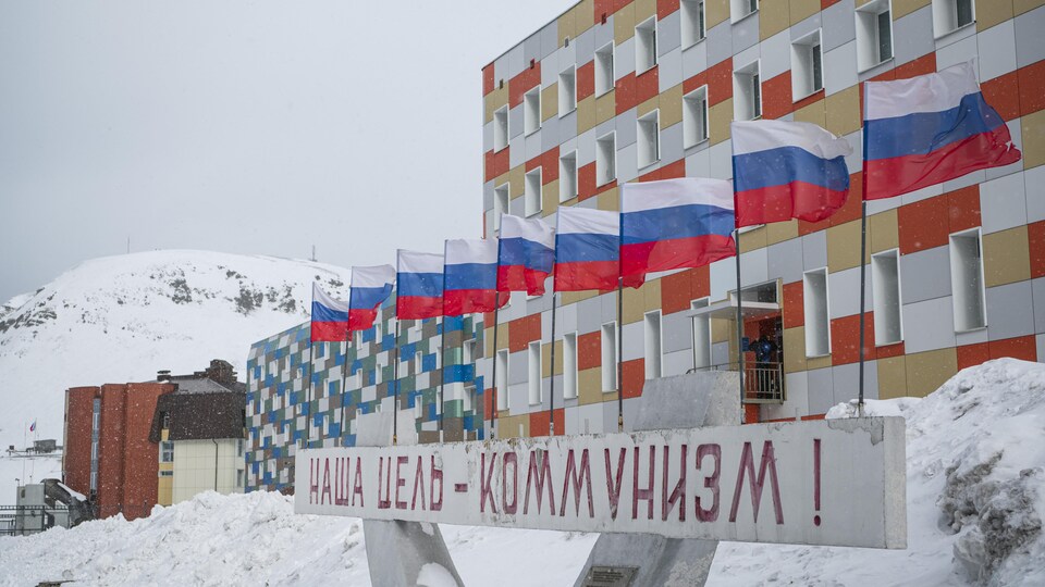 Une enseigne écrite en russe avec des drapeaux russes devant un bâtiment.