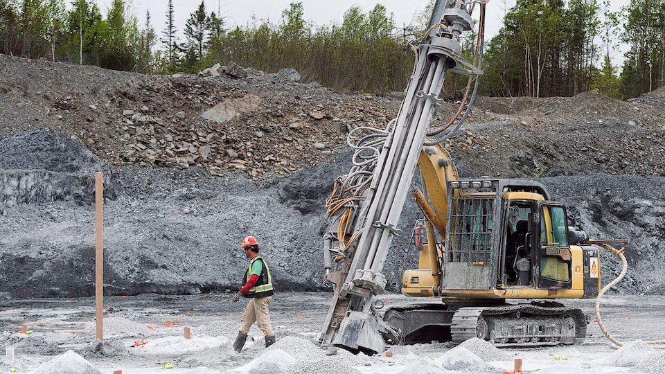 Un travailleur marche sur le site de la mine d'or Touquoy en Nouvelle-Écosse à côté d'une machine.