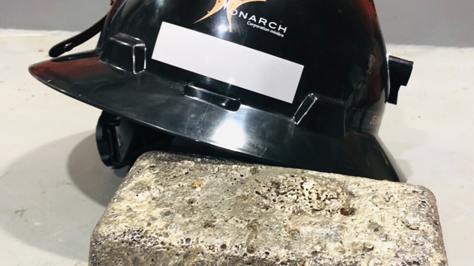 Une photo de lingot d'or avec un casque de mineur à l'effigie de Monarch.