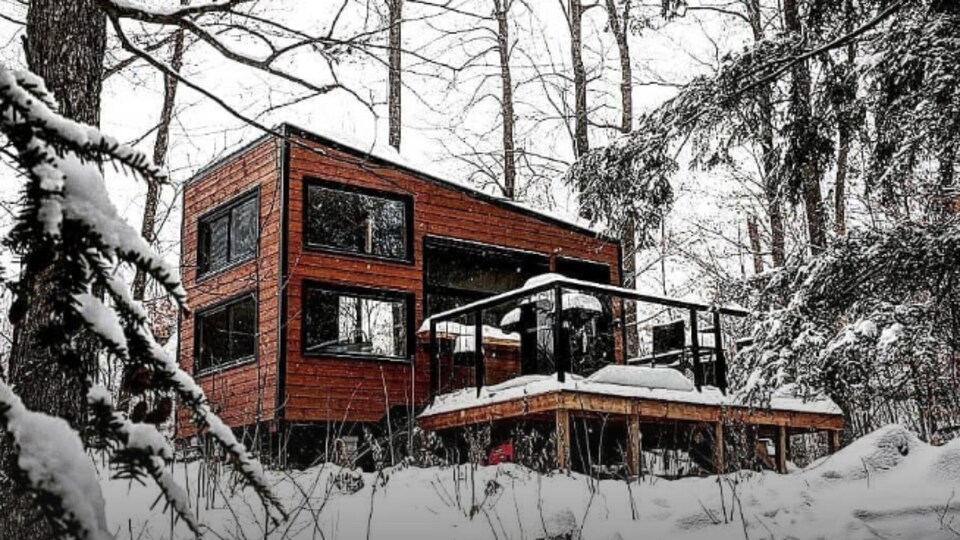 Un mini-chalet dans la forêt, sous la neige.