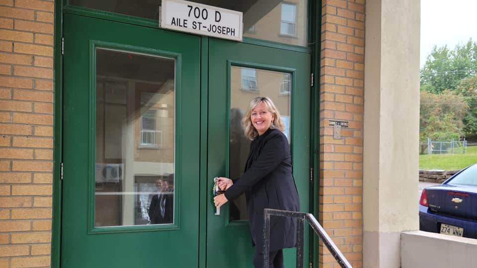 Andrée Laforest sourit en tenant une poignée de porte.