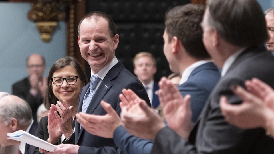 Le ministre des Finances du Québec, Eric Girard, au centre, est applaudi par le premier ministre du Québec, François Legault, à droite, et les membres du gouvernement alors qu'il présente son discours du budget, le mardi 10 mars 2020 à l'Assemblée nationale du Québec.