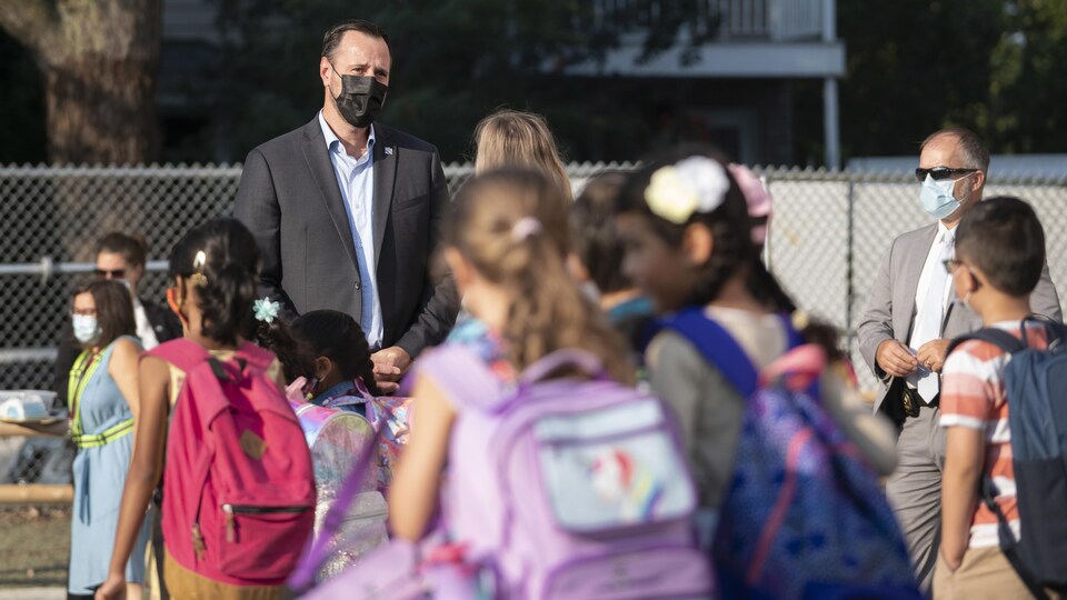 Le ministre de l’Éducation, Jean-François Roberge avec des élèves dans une cour d’école.