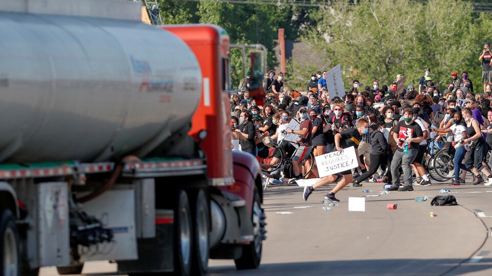Des gens se tassent du centre de la route à l'approche du camion. 