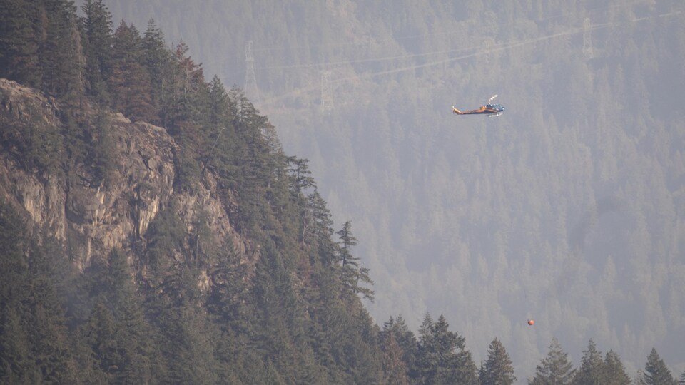 Un hélicoptère survole une forêt enfumée